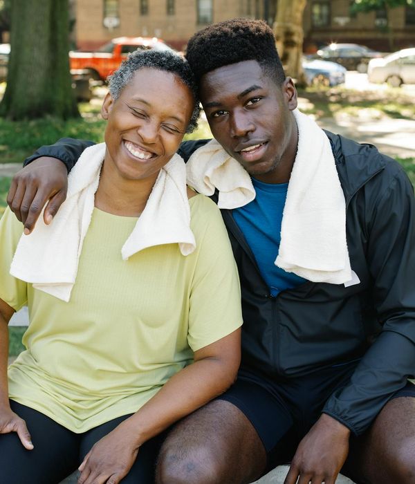 A happy woman in sportswear smiling and feeling energetic in a park at sunrise.